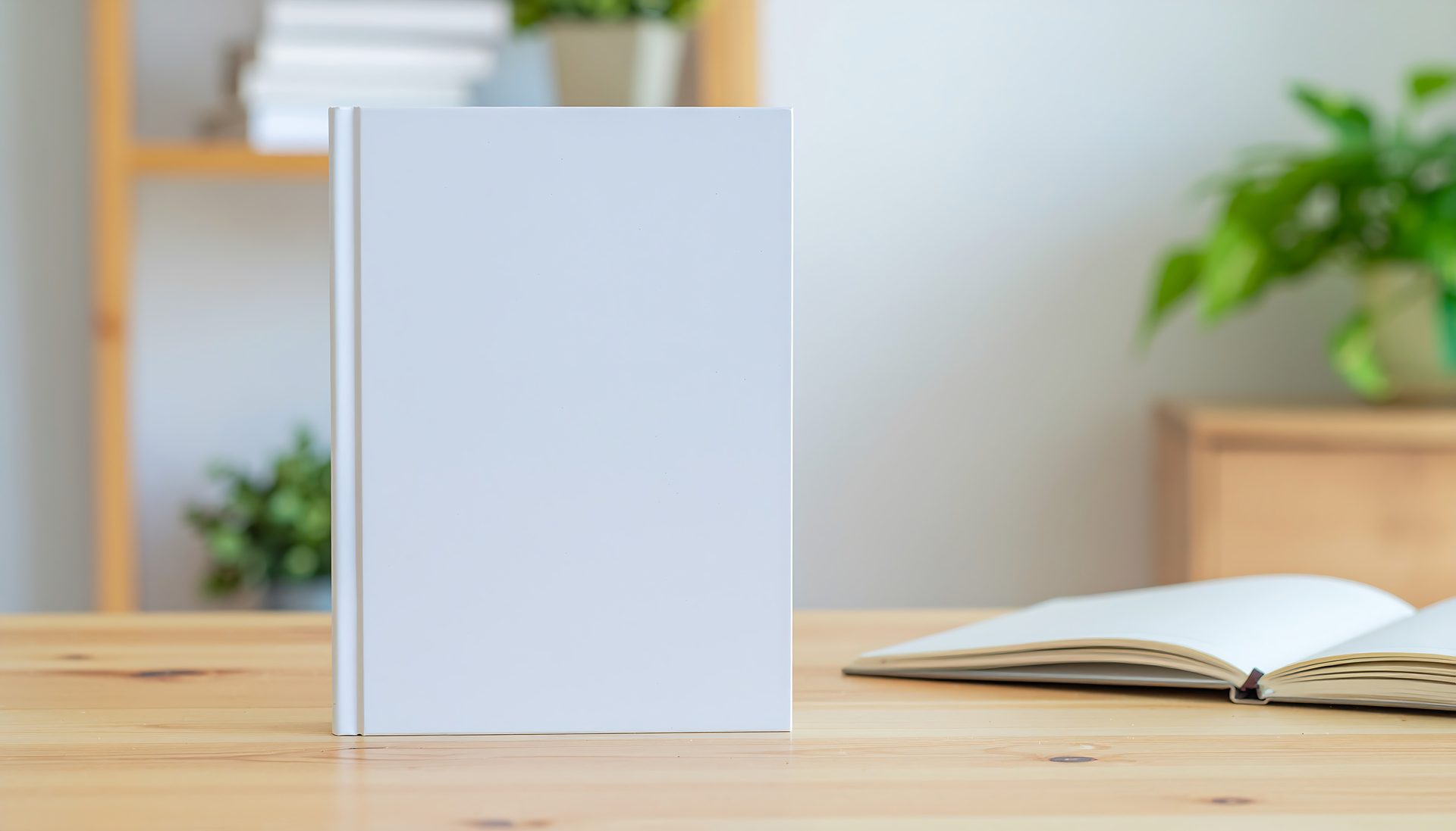 blank white book mockup standing on wooden desk with blurred background